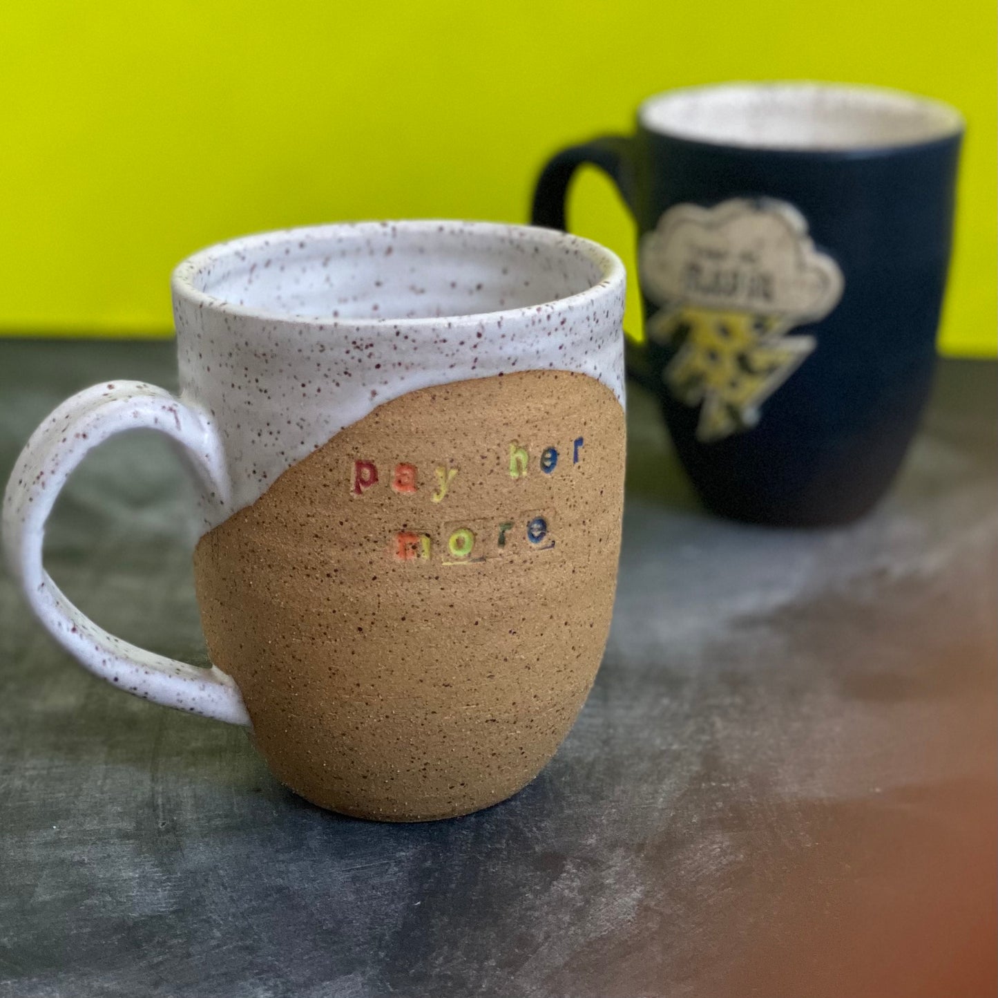 pay her more mug with white glaze and rainbow text
