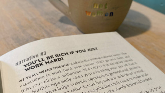 financial feminist book open on table next to fix systems not women mug