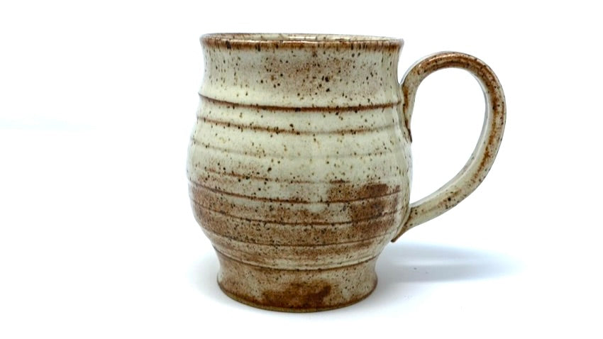 a shino mug with white glaze where thicker and reddish-brown where thinner. horizontal ridges are accentuated by glaze breaks.