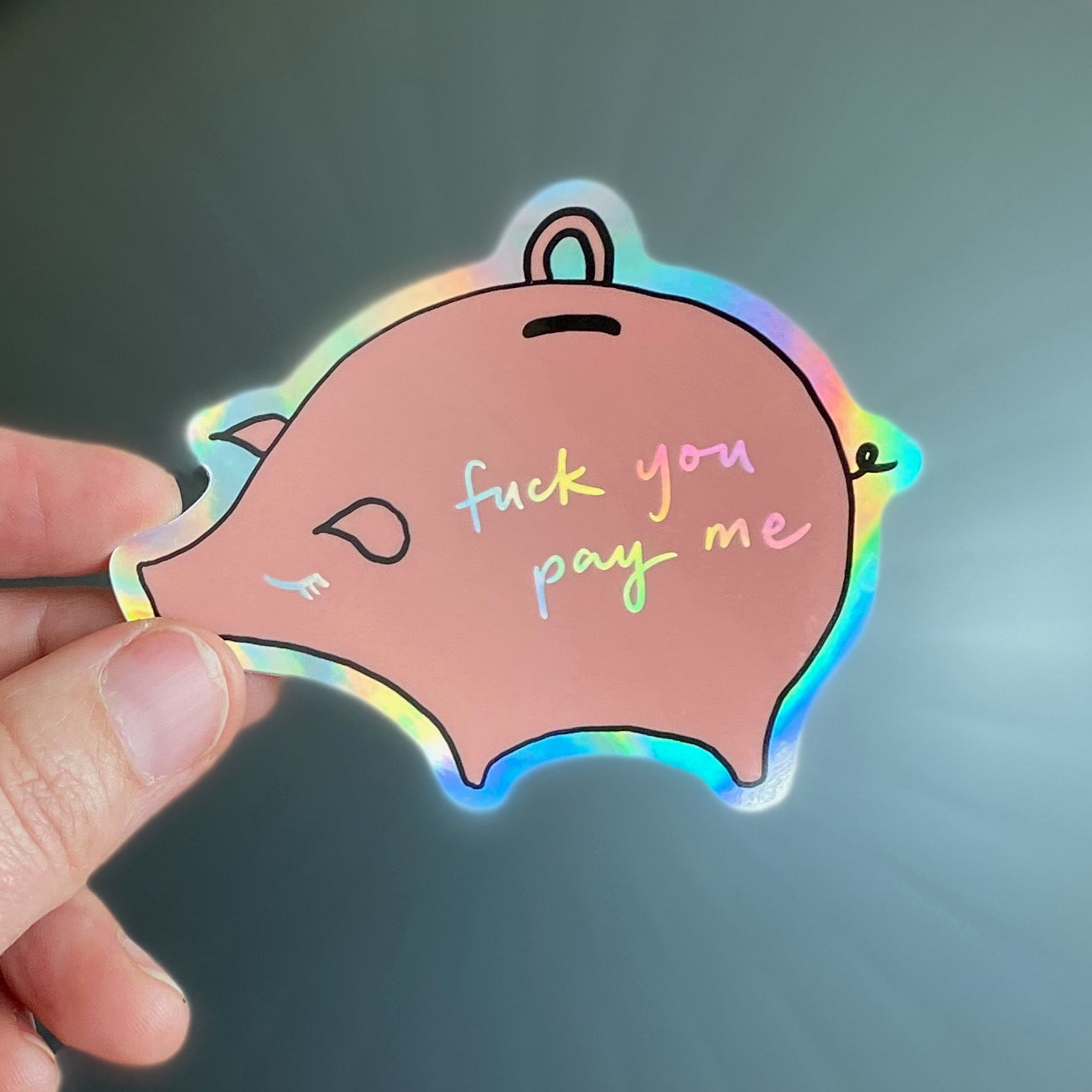 pink piggy bank sticker, with holographic outline, eyelash, and text that reads "fuck you pay me"