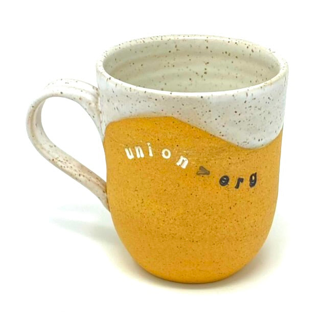 a buff stoneware mug with white glaze inside and on the rim. the words "union > erg" are stamped and inlaid in black and white.
